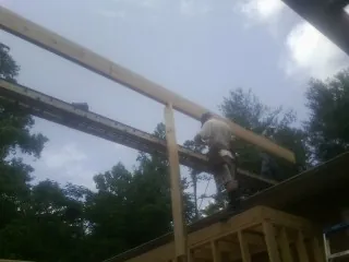 Carpenter setting a ridge beam over a new addition frame — Ice Dam Removal by Roofing Brothers in Placida