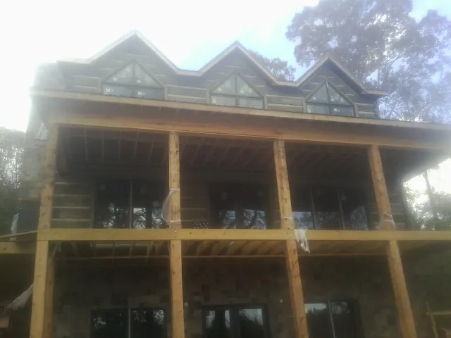 Dormers and porch framing on a large log home under construction — Roof Coating work by our crew in Placida
