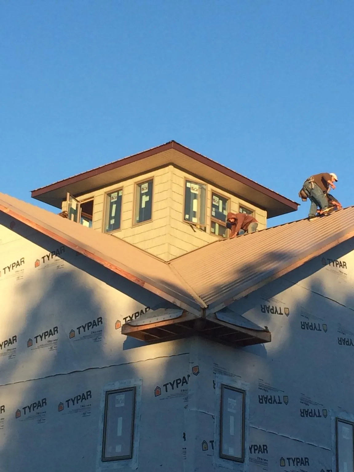 Roofers working around a rooftop cupola on a new metal roof at sunset — Roof Waterproofing in Placida by Roofing Brothers